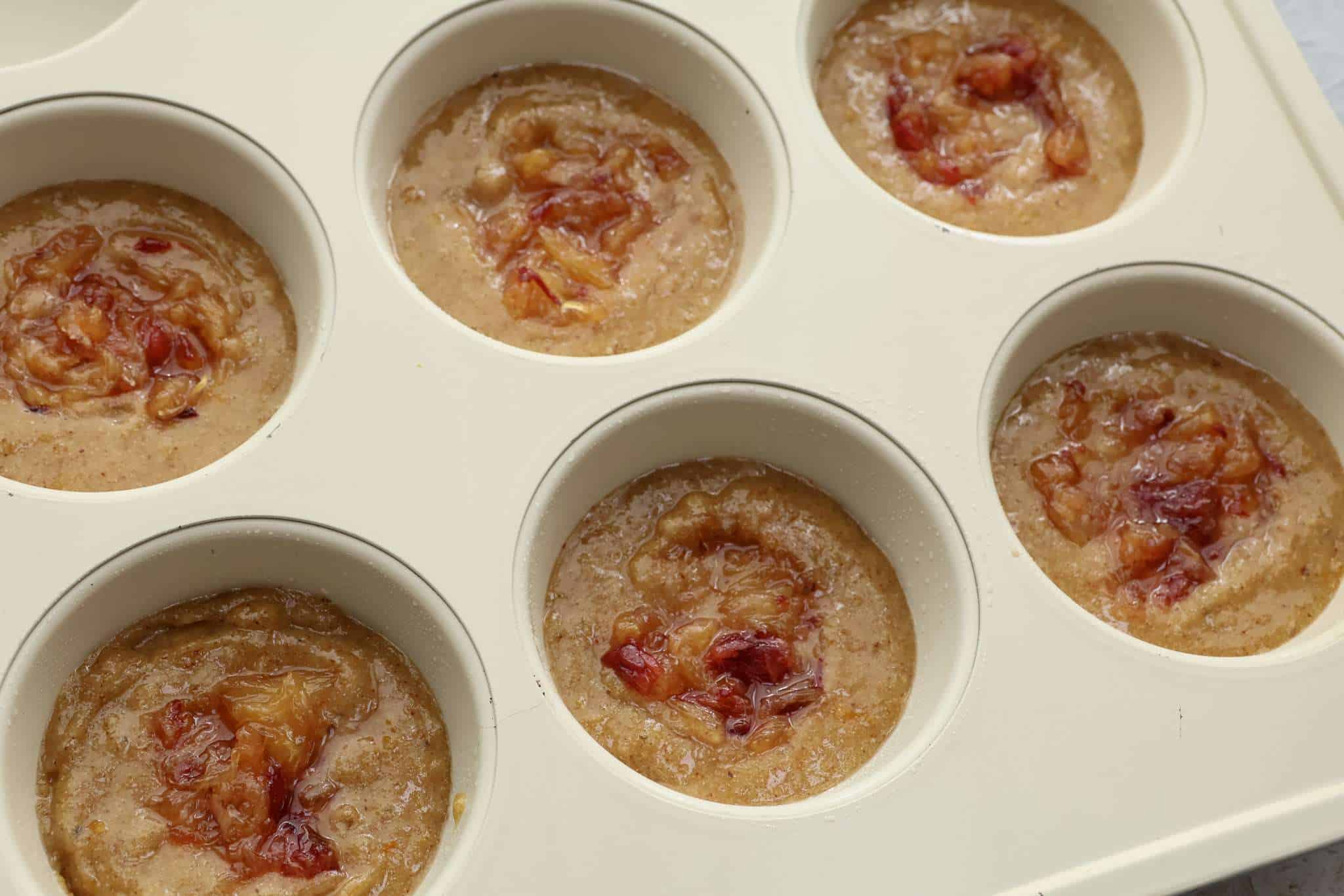 The batter for orange walnut frangipane style cakes in muffin tins and quick orange jam swirled into each