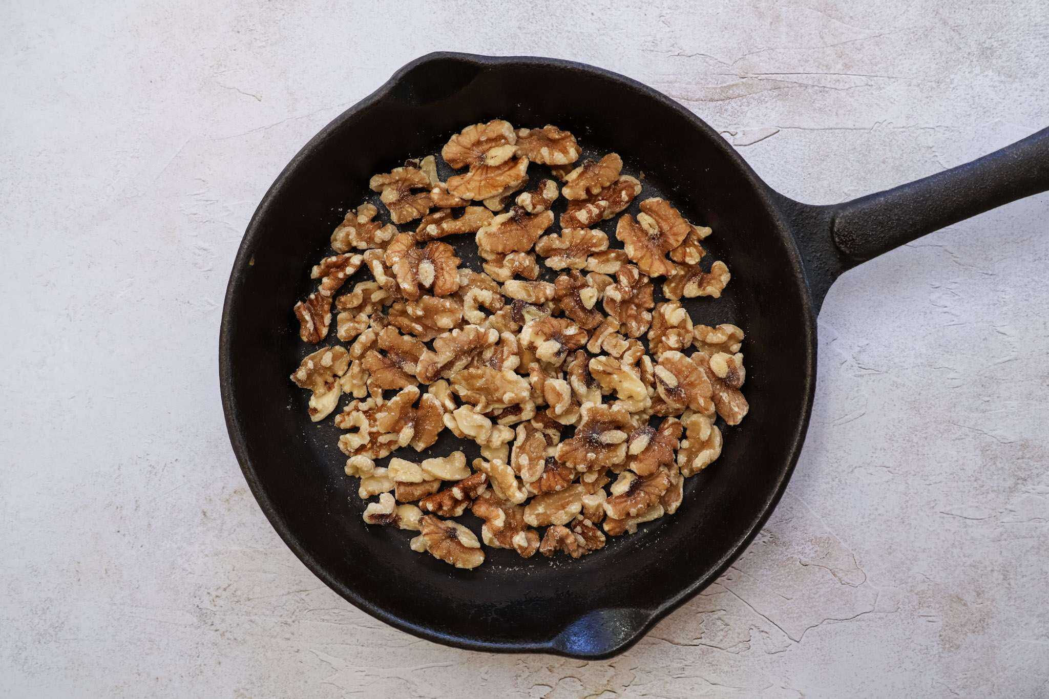 Walnuts toasting in a small cast iron pan