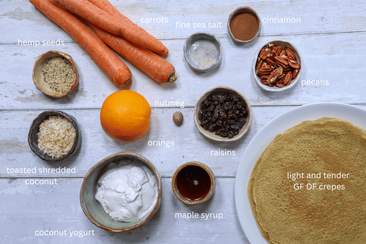 All ingredients for Gluten-Free Carrot Cake Crepes (Dairy-Free) are displayed on a rustic white wooden background and labeled