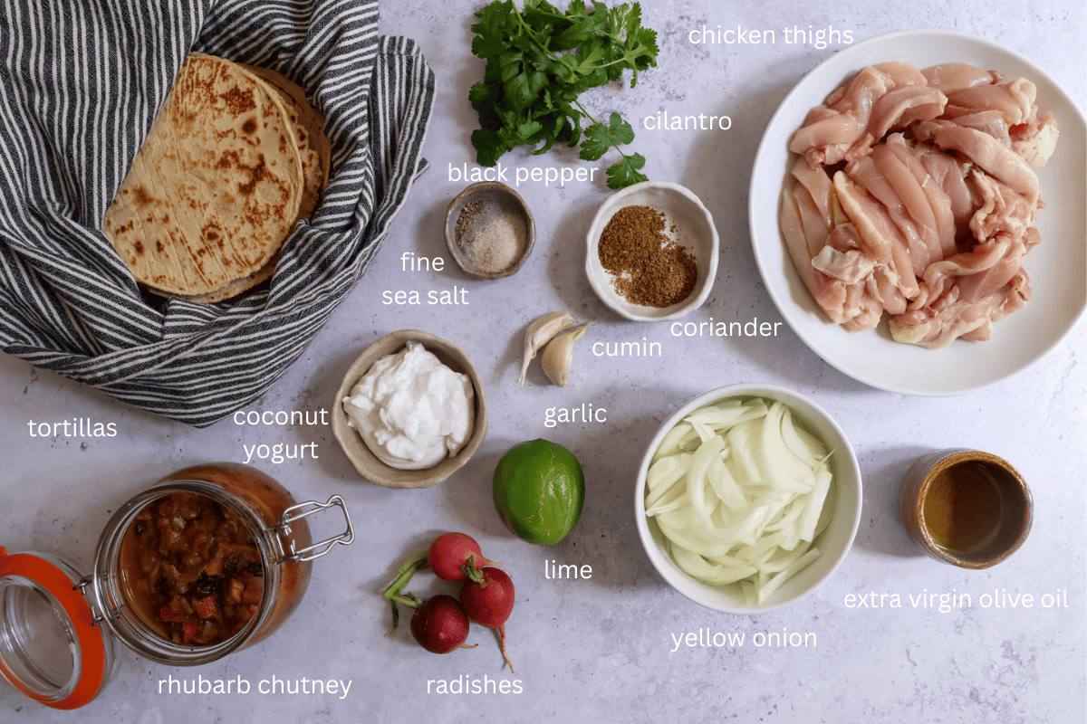 All ingredients for Sheet Pan Chicken Fajita–Style Tacos with Spiced Rhubarb Chutney are displayed on a concrete style background and labeled