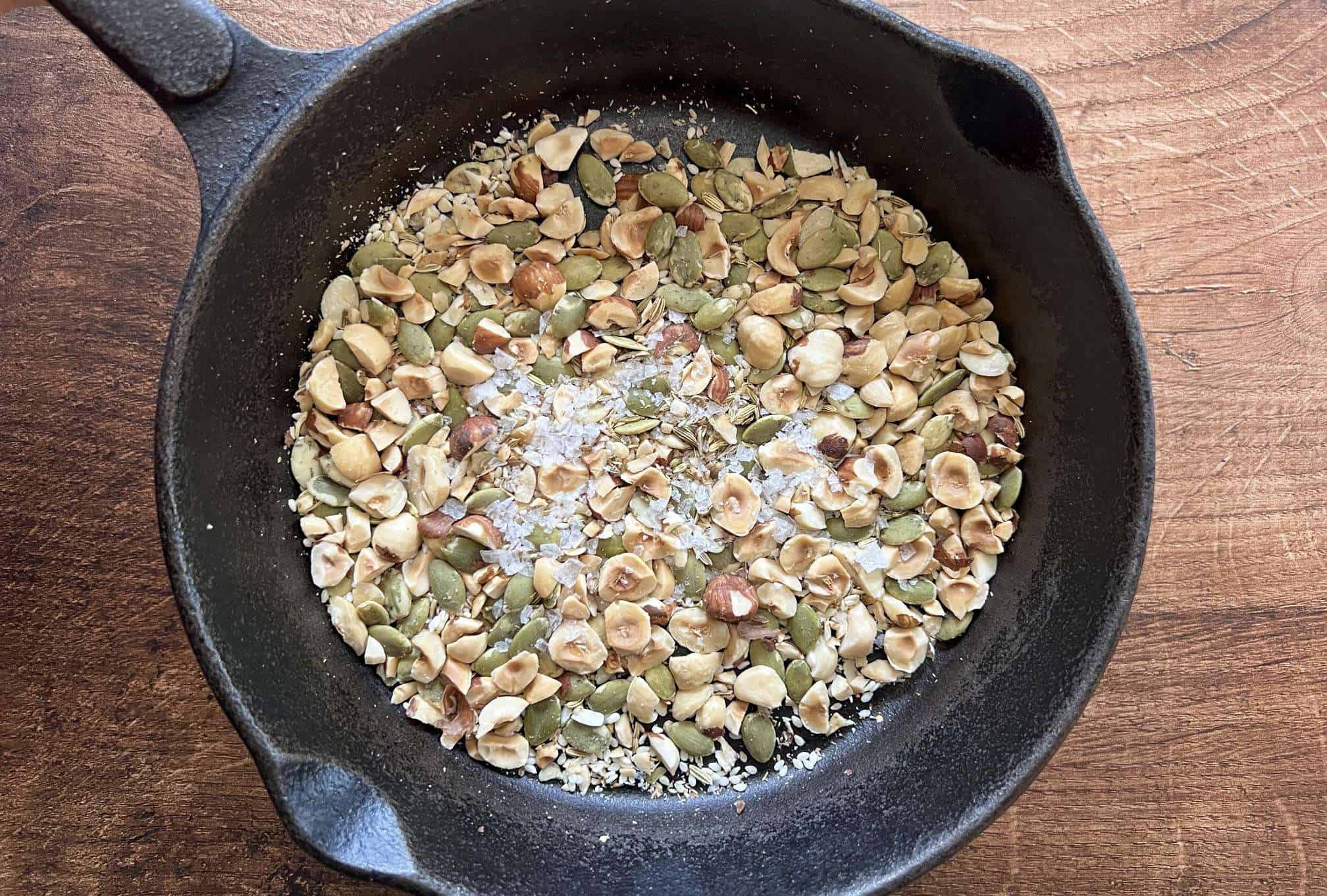 a cast iron pan with hazelnut dukkah toasting in it