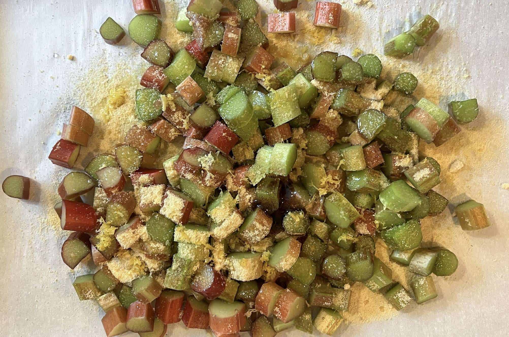 rhubarb tossed with maple sugar, vanilla, and lemon zest ready to roast on a parchment lined baking sheet