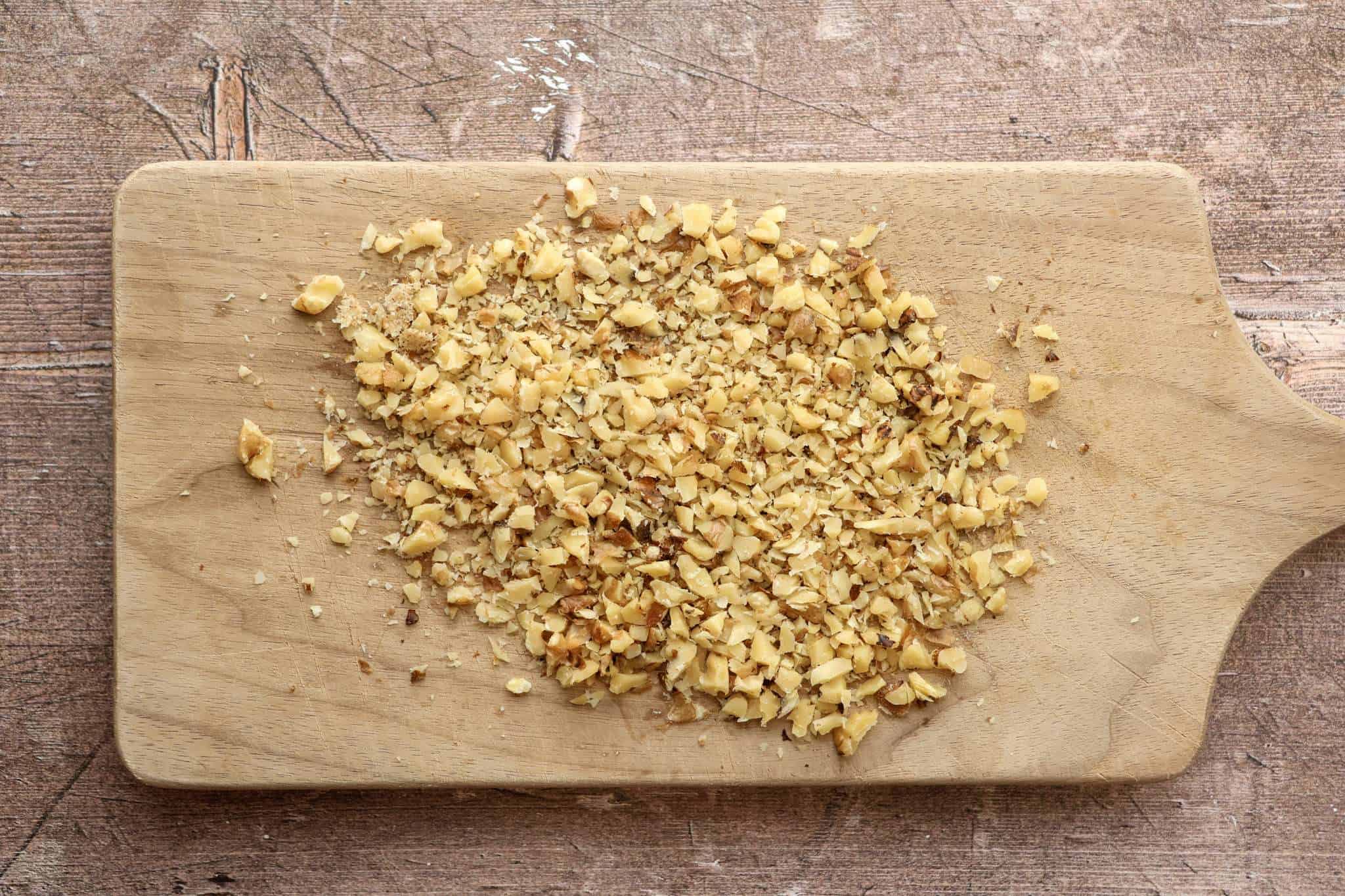 finely chopped toasted walnuts on a wooden board