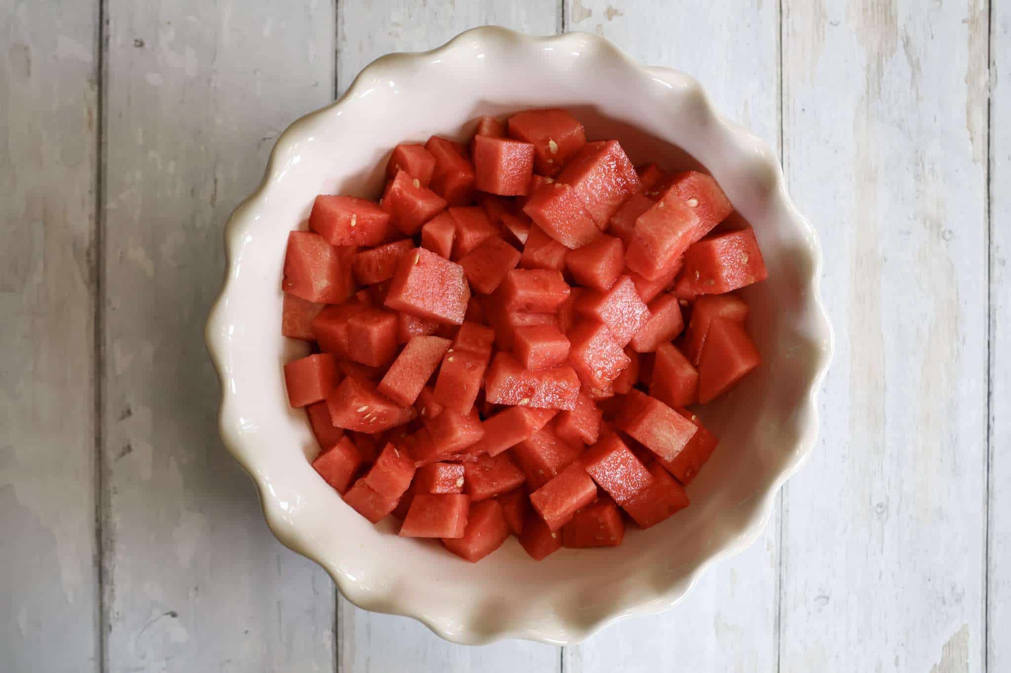 A white bowl filled with cubed watermelon