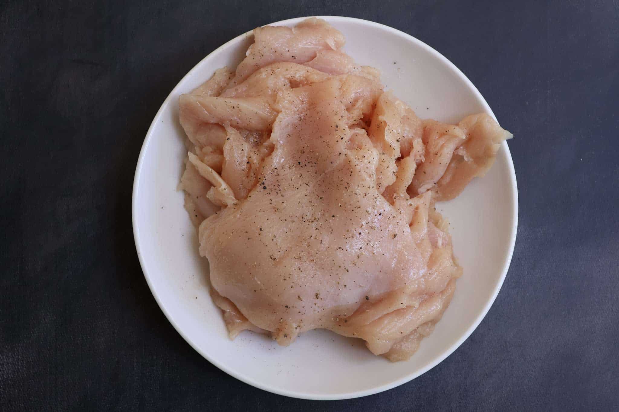 A white plate with thinly pounded chicken breasts