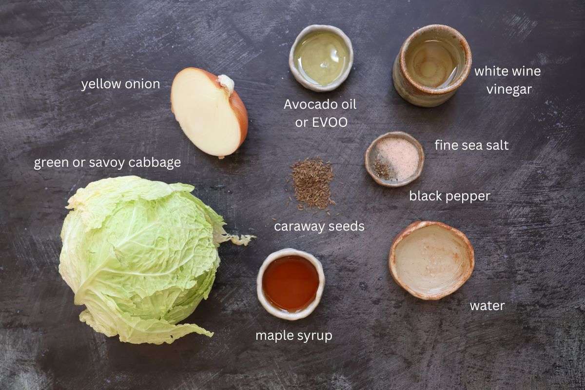 All ingredients for German Krautsalat are displayed on a dark grey surface and labeled