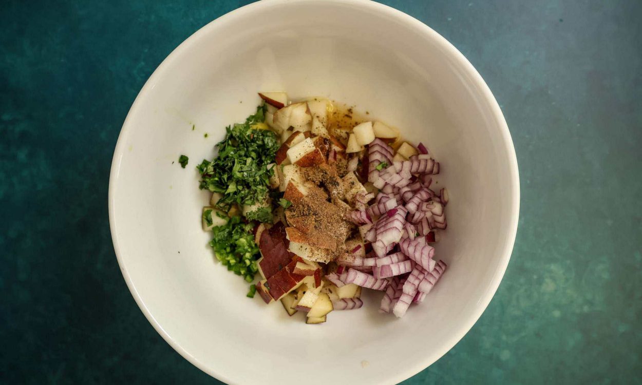 a white bowl containing all ingredients for pear salsa