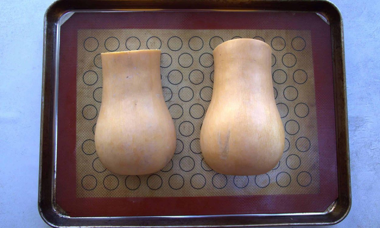 two butternut squash halves on a baking sheet